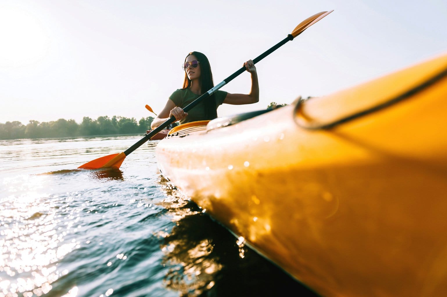 Vrouw peddelt in een gele kano over een zonovergoten rivier tijdens een zomerse tocht – een typisch moment voor actieve kanotochten Duitsland.