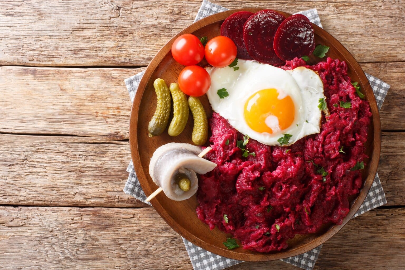Een bord met Labskaus – een traditionele Noord-Duitse specialiteit van aardappelpuree, rode biet en cornedbeef, geserveerd met een spiegelei, augurken, haringrol en tomaten – een van de meest unieke typisch Duitse gerechten.