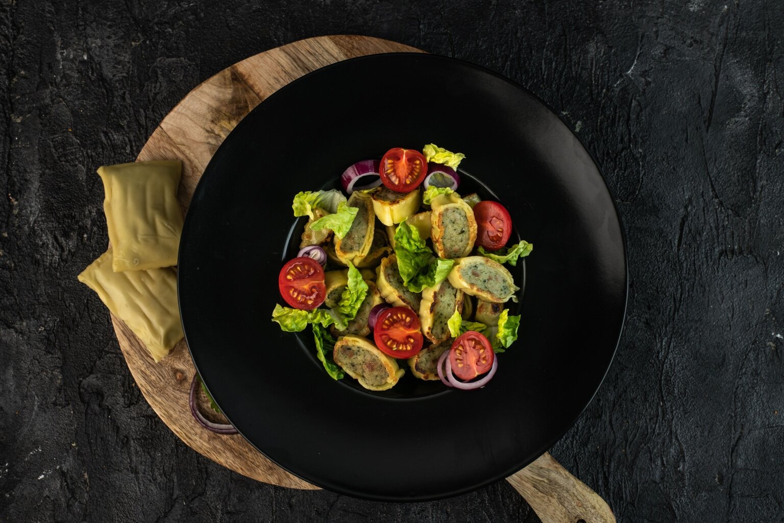 Gesneden en gebakken Maultaschen geserveerd met salade, kerstomaatjes en rode ui – een hartig pastagerecht uit Zwaben en een van de bekendste typisch Duitse gerechten.