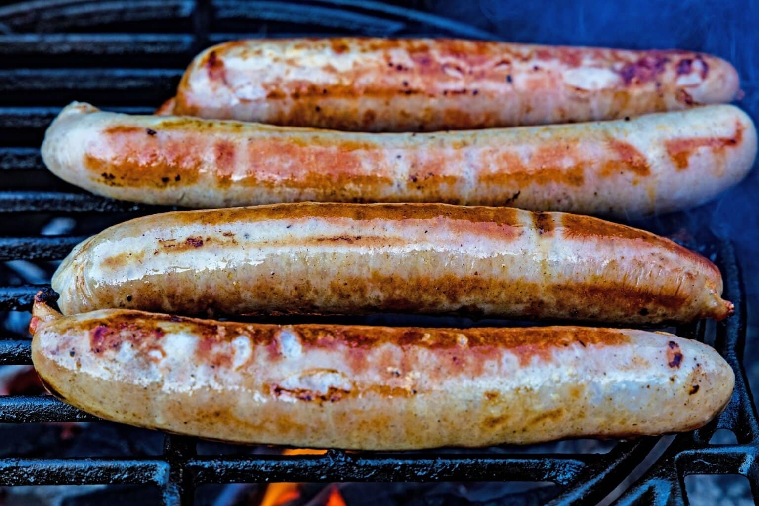 Gegrilde Bratwurst op een houtskoolbarbecue – een van de typisch Duitse gerechten die je geproefd moet hebben tijdens een culinaire reis door Duitsland.