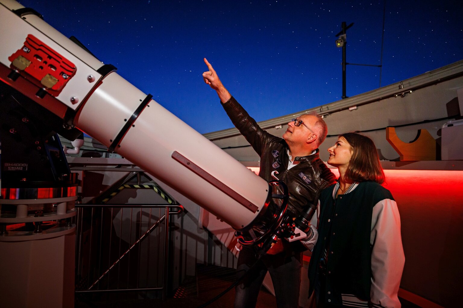 Sterrenkijkers bij groot telescoop in observatorium tijdens zuiden night, waar een man en vrouw samen de hemel en fonkelende sterren bewonderen.