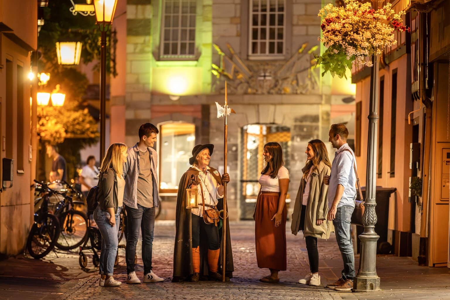 Een groep bezoekers tijdens een nachtwandeltocht met een nachtwacht in de historische binnenstad van Ahrweiler in het Ahrdal. De sfeervolle verlichting en middeleeuwse setting laten de cultuur en geschiedenis van het Ahrdal tot leven komen.