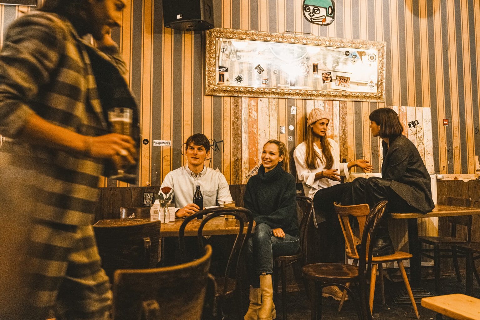 Vrienden lachen en praten in een gezellige bar tijdens een Stuttgart party, waar warme lichten en gesprekken de nacht vullen met sfeer en muziek.