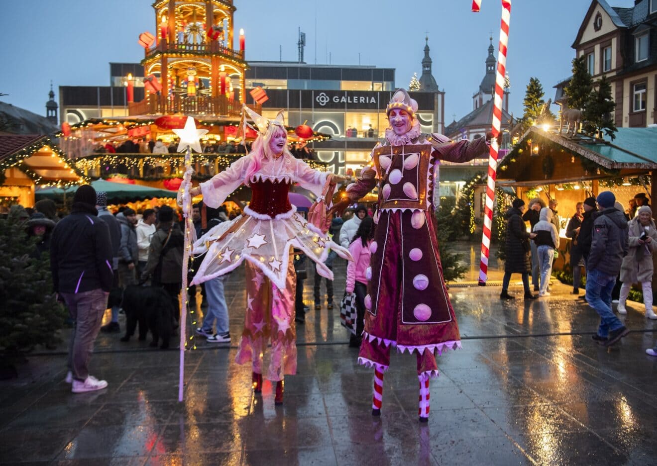 Kostuumartiesten op stelten tussen de bezoekers van de kerstmarkt in Fulda