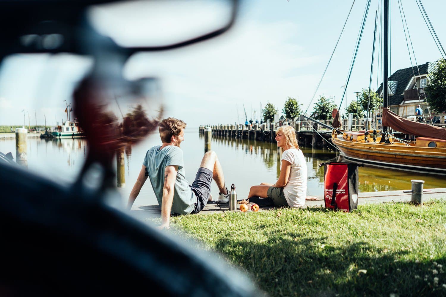 Fietsers pauzeren in het gras aan de haven van het Oostzeebad Ahrenshoop