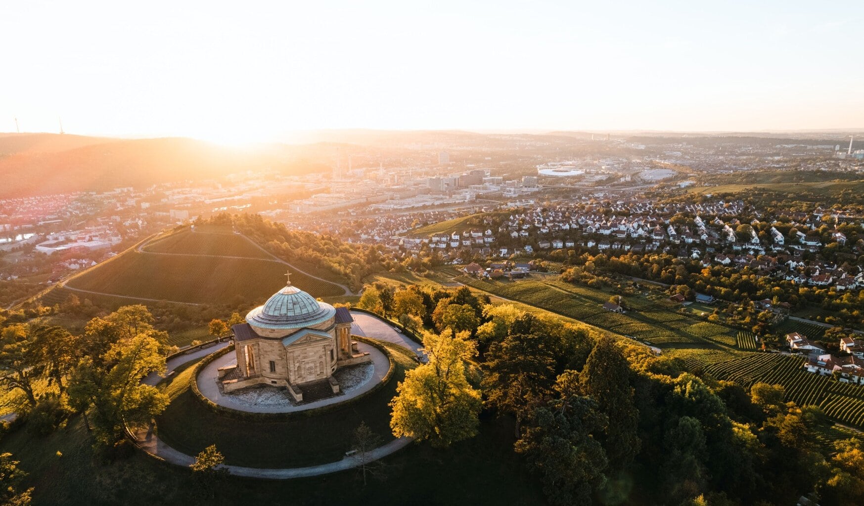 Zonsondergang boven Stuttgart met uitzicht op de grafkapel tussen glooiende wijngaarden, waar stilte voorafgaat aan de nacht van een Stuttgart party.
