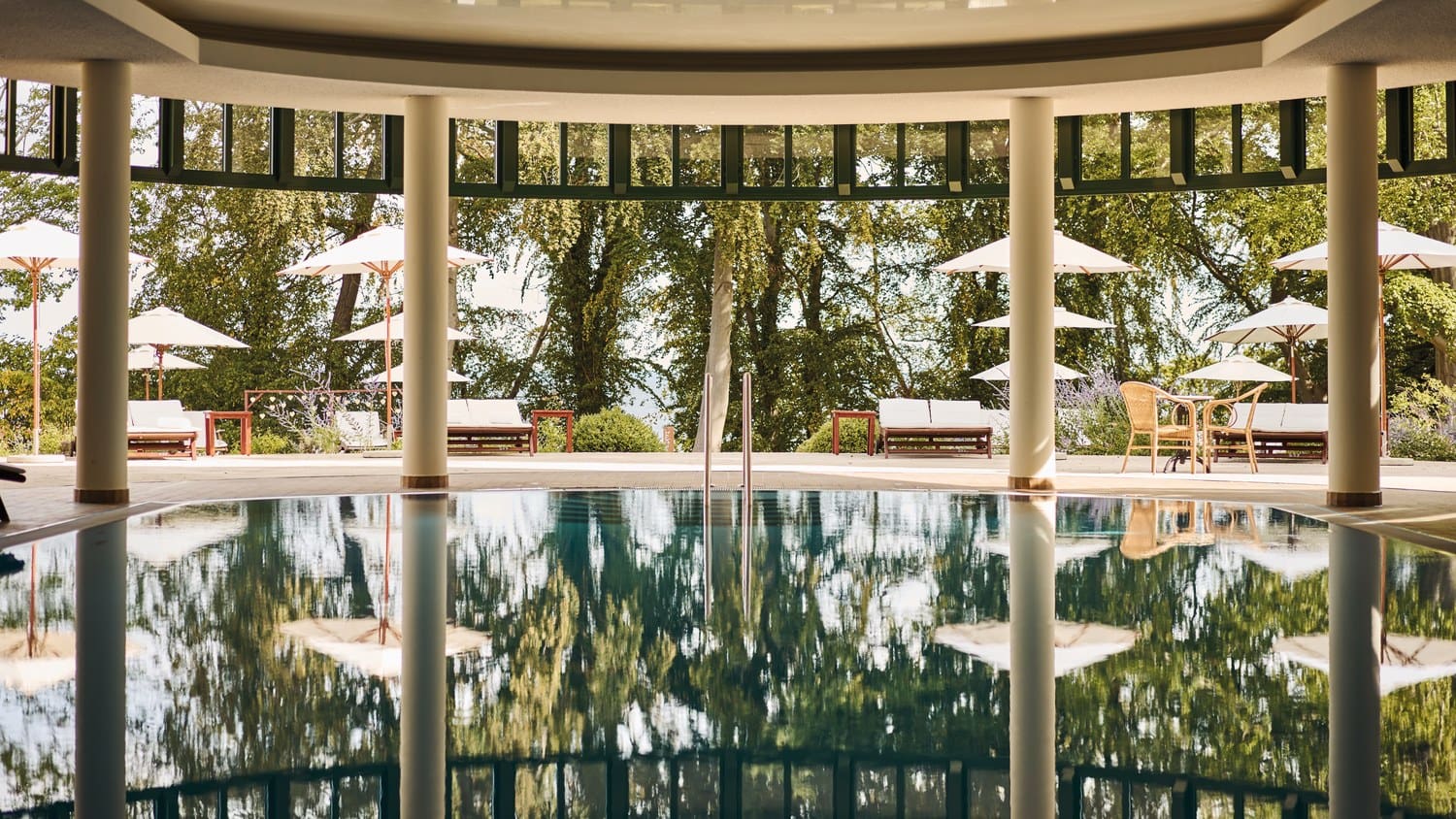 Binnenbad met zuilen en uitzicht op de tuin in het aja Nordperd & Villen in Göhren op Rügen