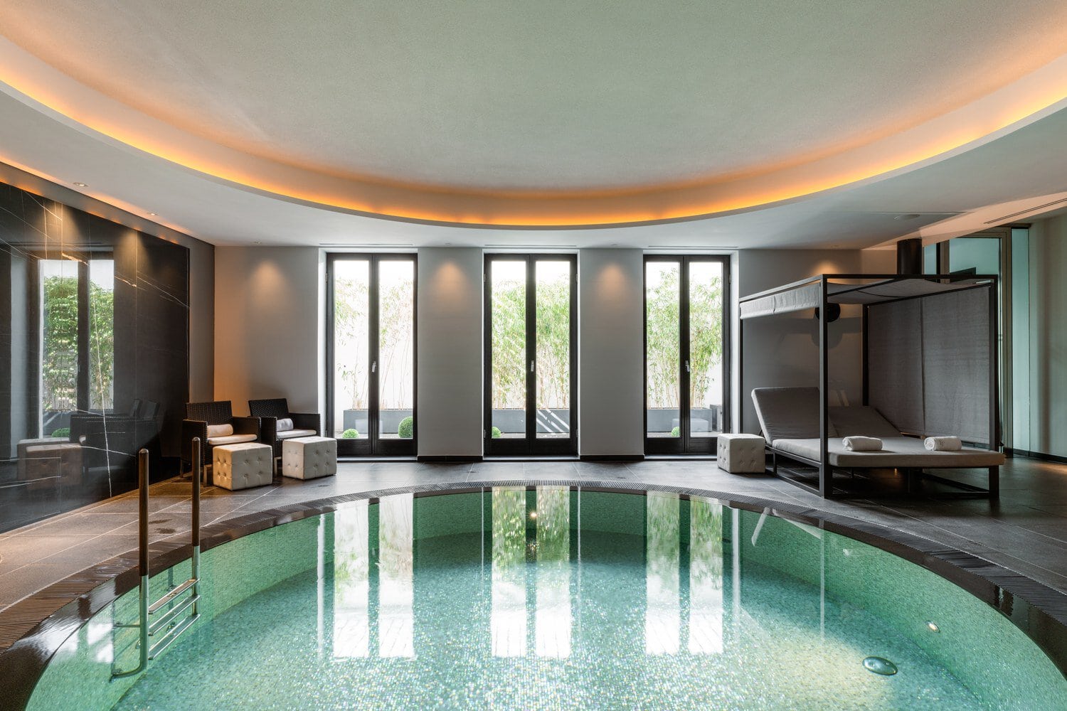 Rond binnenbad met ligbedden in de minimalistische spa van designhotel CERES am Meer in Binz