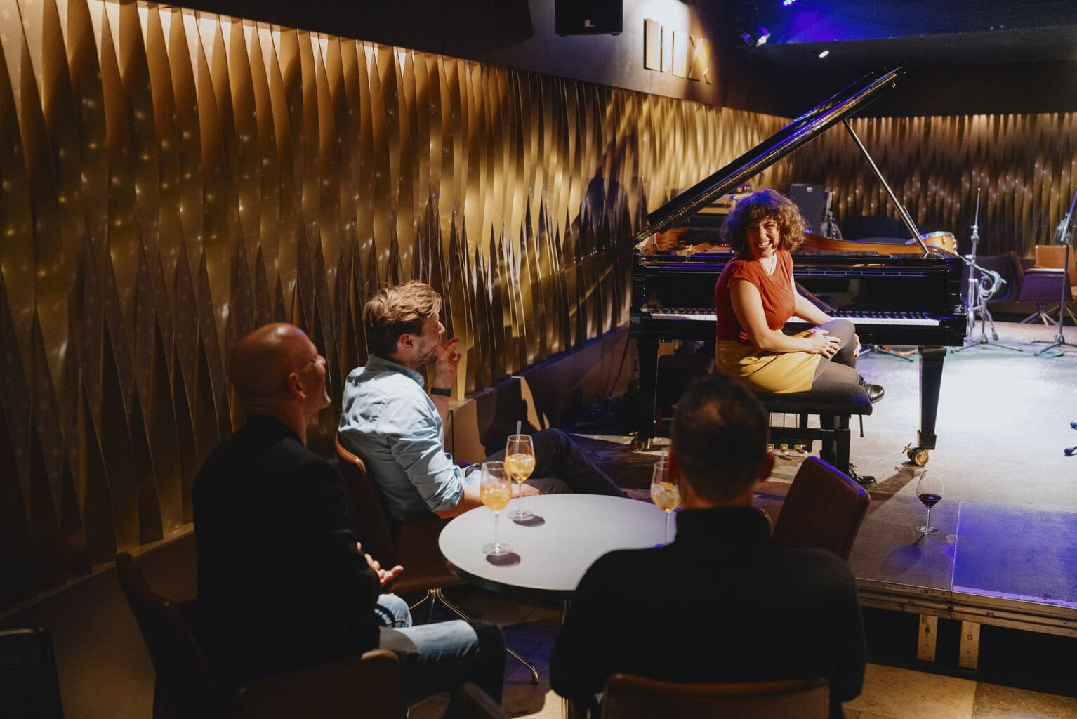 Intieme jazzclub in zacht goudlicht, waar muziek en lachen samenkomen tijdens een stijlvolle Stuttgart party vol sfeer en warme tonen.