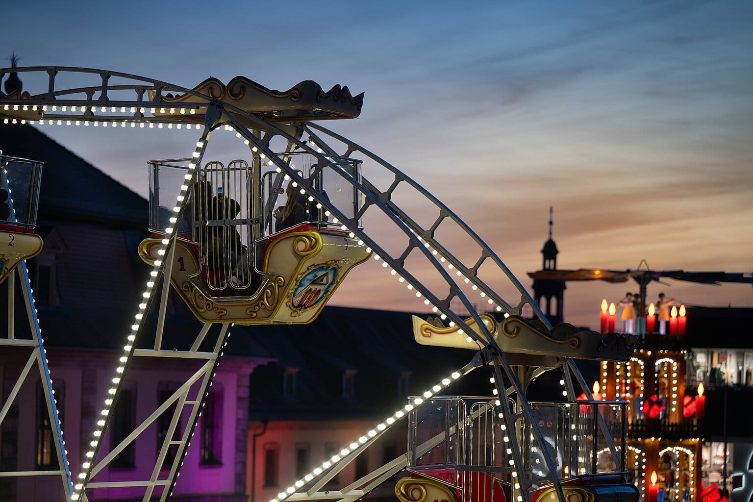 Verlicht nostalgisch reuzenrad met op de achtergrond de kerstpiramide in Fulda