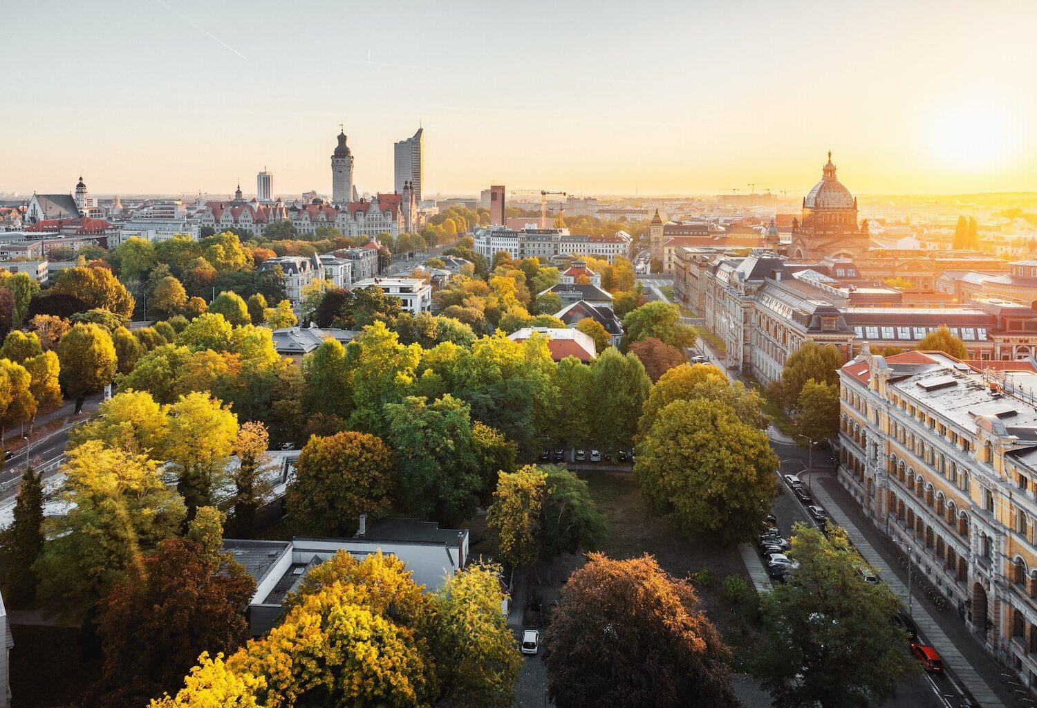 Panorama van de skyline van de Duitse stad Leipzig. Te zien zijn een wolkenkrabber, het nieuwe stadhuis, het Bundesverwaltungsgericht en de architectuur van Leipzig, gelegen tussen de groene natuur en herfstbomen
