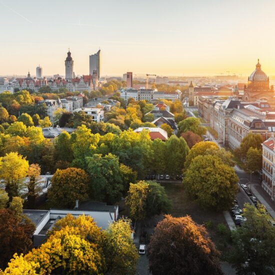 Panorama van de skyline van de Duitse stad Leipzig. Te zien zijn een wolkenkrabber, het nieuwe stadhuis, het Bundesverwaltungsgericht en de architectuur van Leipzig, gelegen tussen de groene natuur en herfstbomen