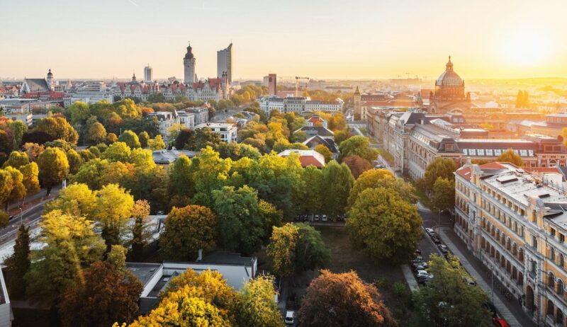 Panorama van de skyline van de Duitse stad Leipzig. Te zien zijn een wolkenkrabber, het nieuwe stadhuis, het Bundesverwaltungsgericht en de architectuur van Leipzig, gelegen tussen de groene natuur en herfstbomen