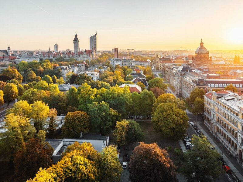 Panorama van de skyline van de Duitse stad Leipzig. Te zien zijn een wolkenkrabber, het nieuwe stadhuis, het Bundesverwaltungsgericht en de architectuur van Leipzig, gelegen tussen de groene natuur en herfstbomen