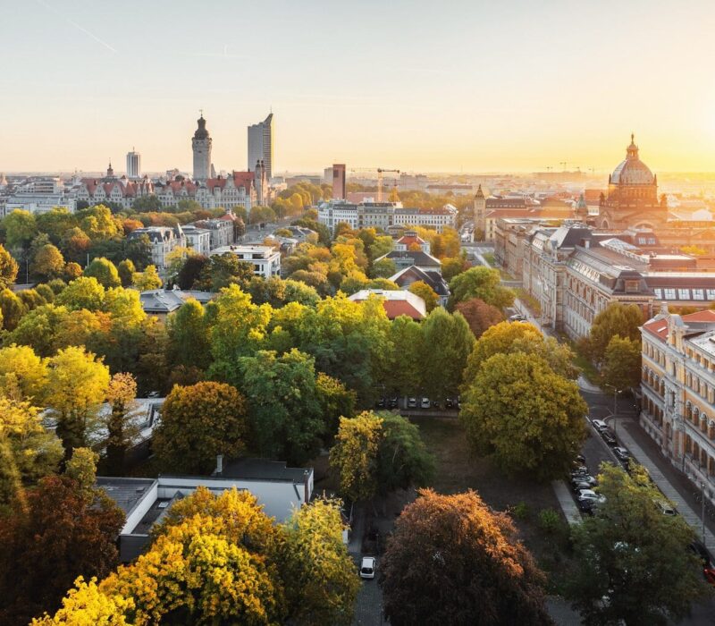 Panorama van de skyline van de Duitse stad Leipzig. Te zien zijn een wolkenkrabber, het nieuwe stadhuis, het Bundesverwaltungsgericht en de architectuur van Leipzig, gelegen tussen de groene natuur en herfstbomen