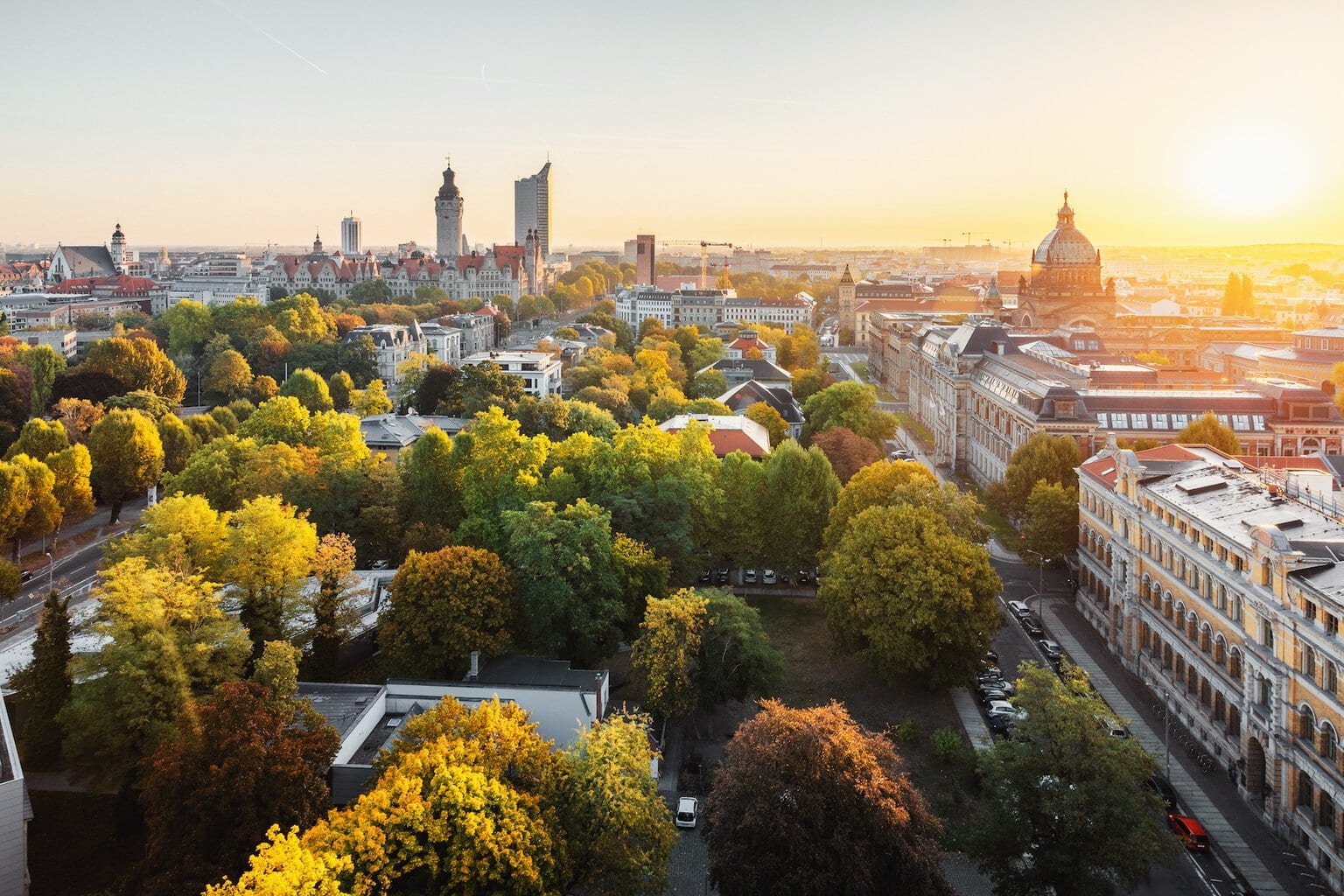 Panorama van de skyline van de Duitse stad Leipzig. Te zien zijn een wolkenkrabber, het nieuwe stadhuis, het Bundesverwaltungsgericht en de architectuur van Leipzig, gelegen tussen de groene natuur en herfstbomen