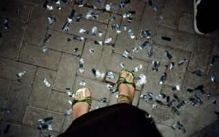 Glinsterend confetti op straat na een Stuttgart party, waar dansende voeten in groene sandalen herinneren aan de nacht vol ritme en vrijheid.