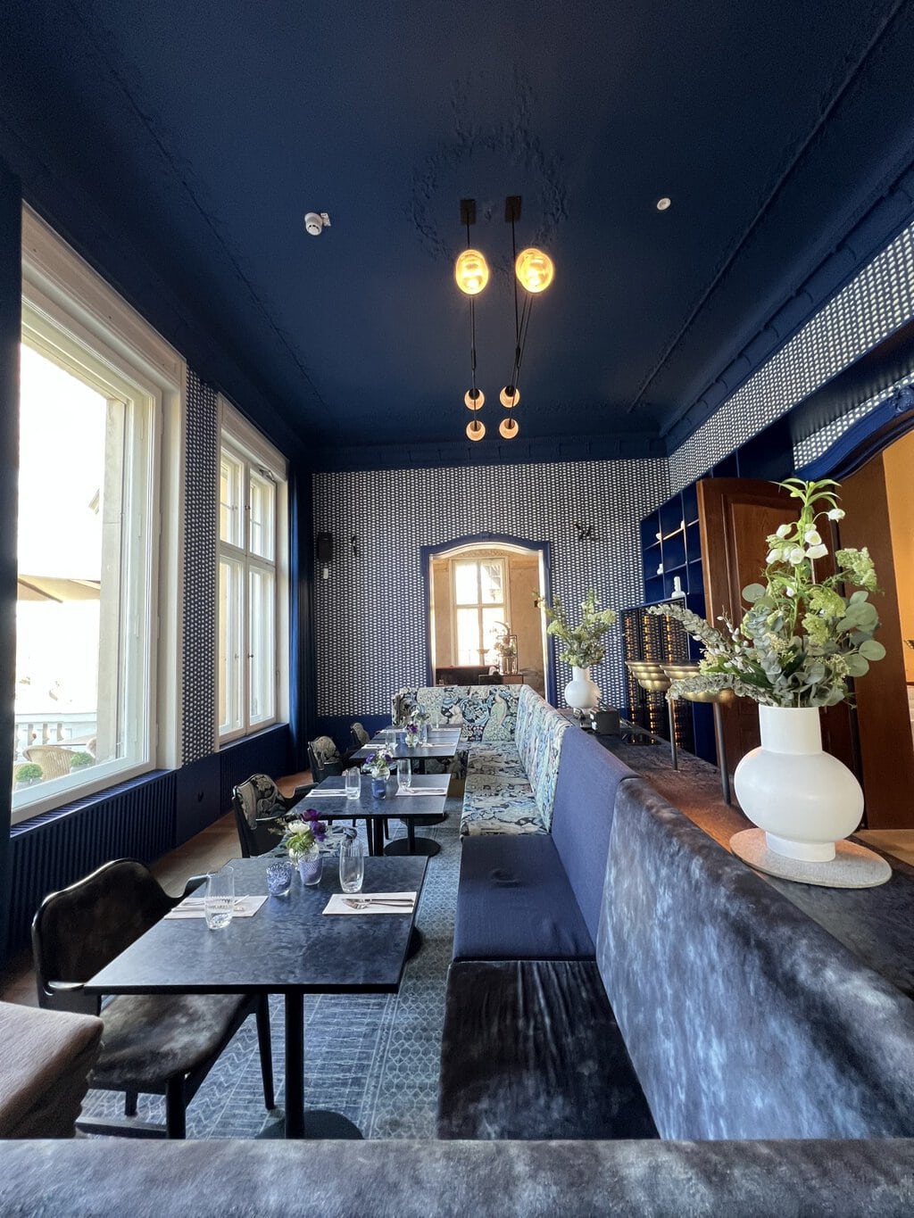 Zacht licht valt door hoge ramen in een stijlvol restaurant, waar moderne elegantie en rust samenkomen – een van de verfijnde Geheimtips Potsdam.