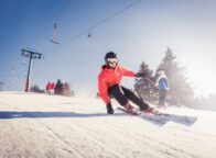 Een skiër snijdt door glinsterende sneeuw onder een stralende hemel, waar snelheid en zonlicht samen het ultieme Sneeuwplezier Zwarte Woud tonen.