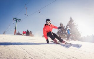 Een skiër snijdt door glinsterende sneeuw onder een stralende hemel, waar snelheid en zonlicht samen het ultieme Sneeuwplezier Zwarte Woud tonen.