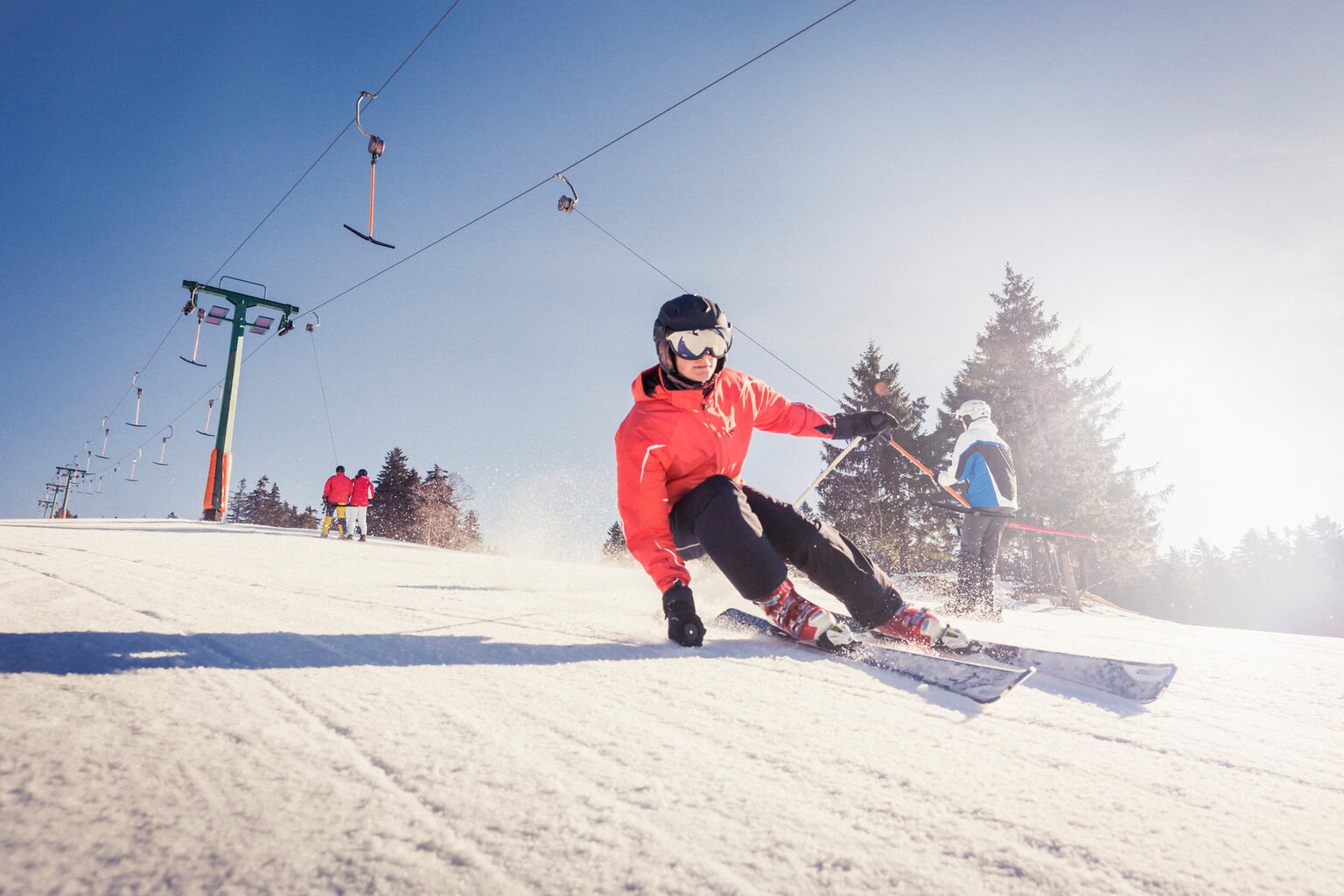Een skiër snijdt door glinsterende sneeuw onder een stralende hemel, waar snelheid en zonlicht samen het ultieme Sneeuwplezier Zwarte Woud tonen.
