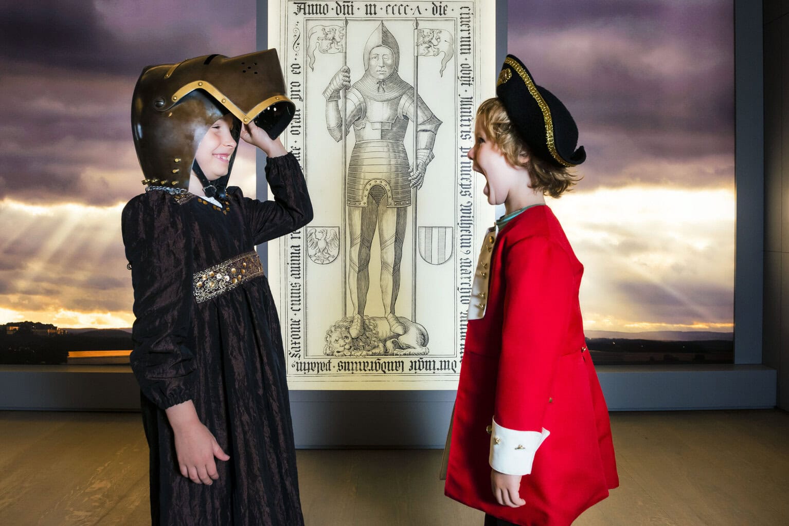 Kinderen verkleed als ridder en edelman lachen in een museum op de vesting Königstein, waar de Saksisch-Zwitserland geschiedenis tot leven komt.