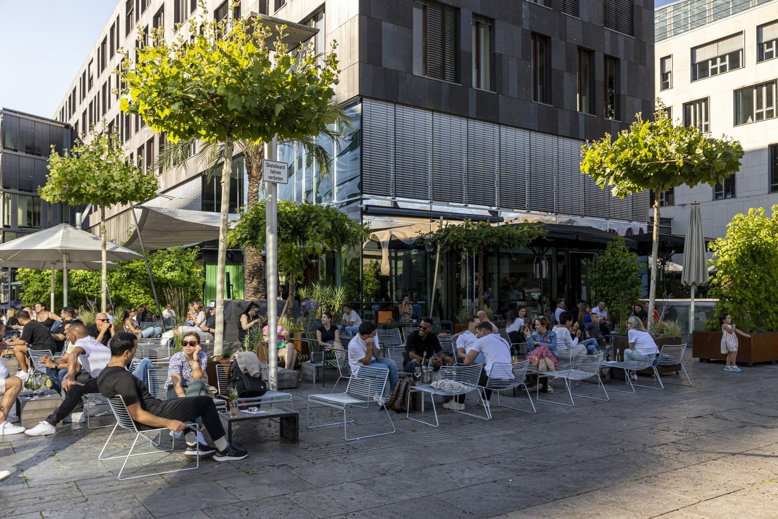 Zonovergoten terras in het hart van de stad waar mensen genieten van drankjes en gesprekken, de perfecte start van een bruisende Stuttgart party.