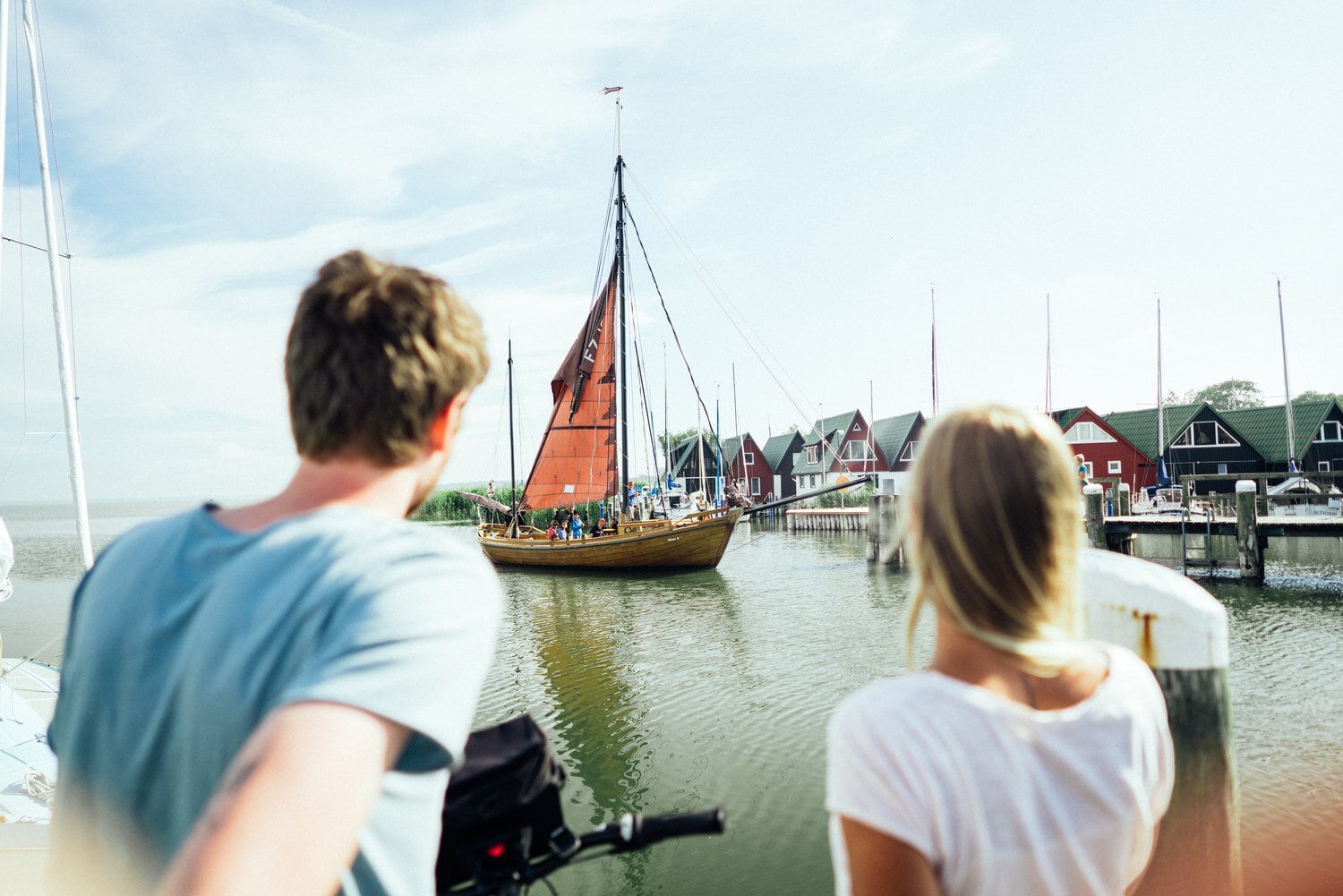 Bezoekers kijken naar een binnenvarende zeesboot in de haven van Ahrenshoop