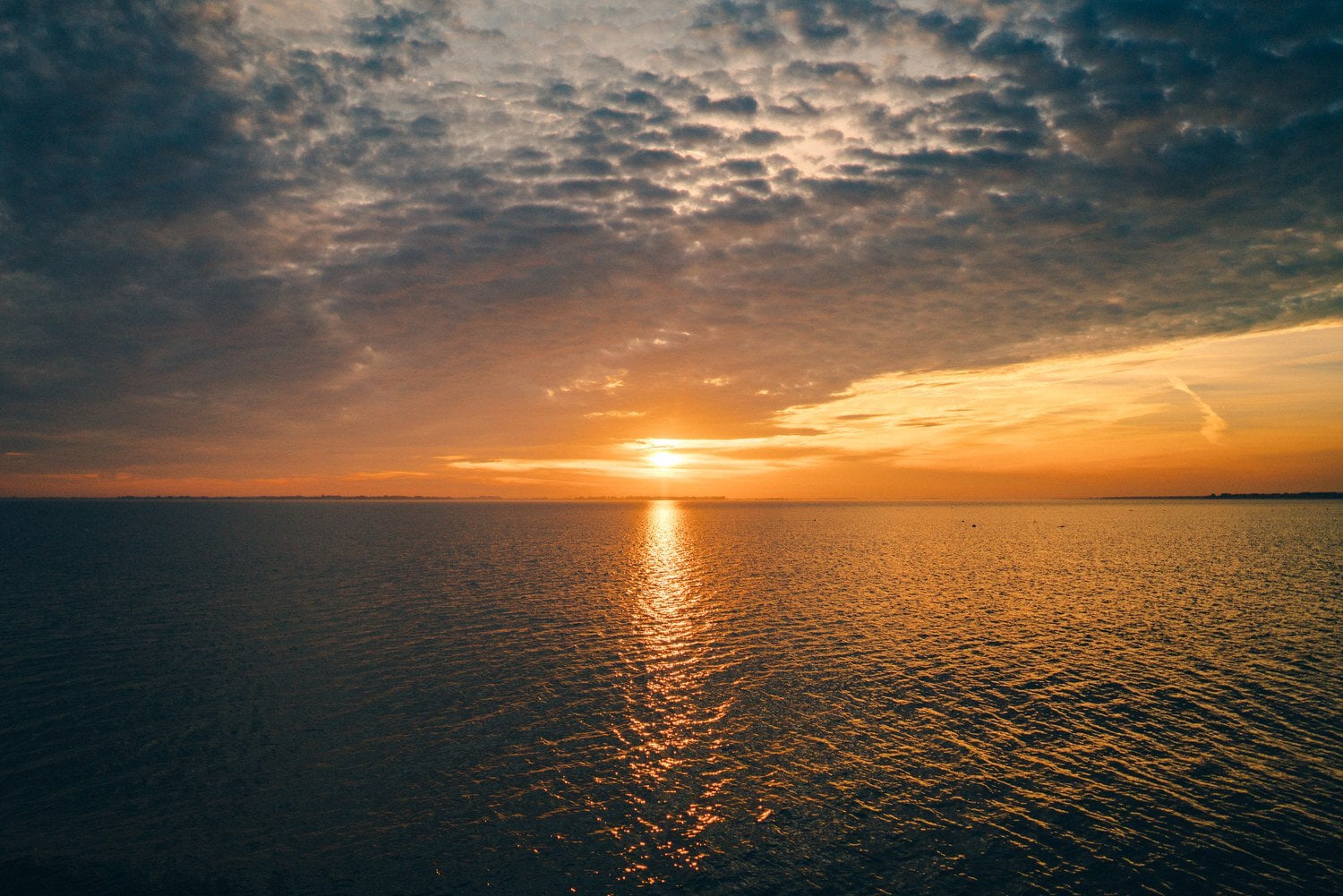Zonsondergang boven het rustige water van de Barther Bodden