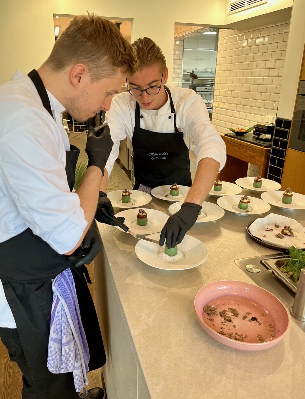 Twee jonge chefs die met precisie een verfijnd gerecht dresseren, waar moderne gastronomie en vakmanschap de smaken van Saarland Rijnland-Palts tot leven brengen.