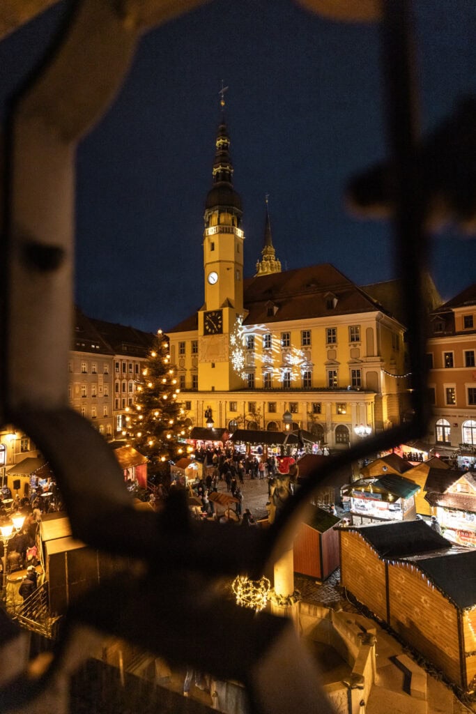 Blik door een smeedijzeren hek op de Wenzelsmarkt op de Hauptmarkt in Bautzen met kerstboom en stadhuis