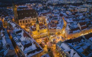 Besneeuwde oude stad van Bautzen tijdens het blauwe uur vanuit de lucht, met het verlichte stadhuis, de Sint-Petrusdom en de Wenzelsmarkt met kerstboom op de Hauptmarkt