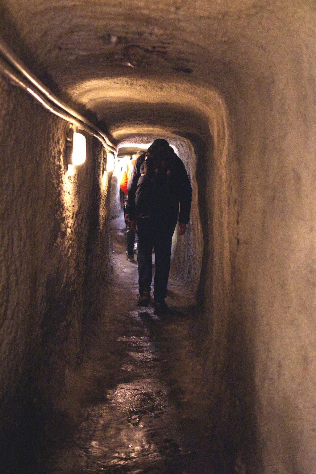 Bezoekers lopen door een smalle, sfeervol verlichte ondergrondse gang in Neurenberg, een spannende historische ervaring die perfect past bij Nürnberg activiteiten tijdens een weekendtrip.