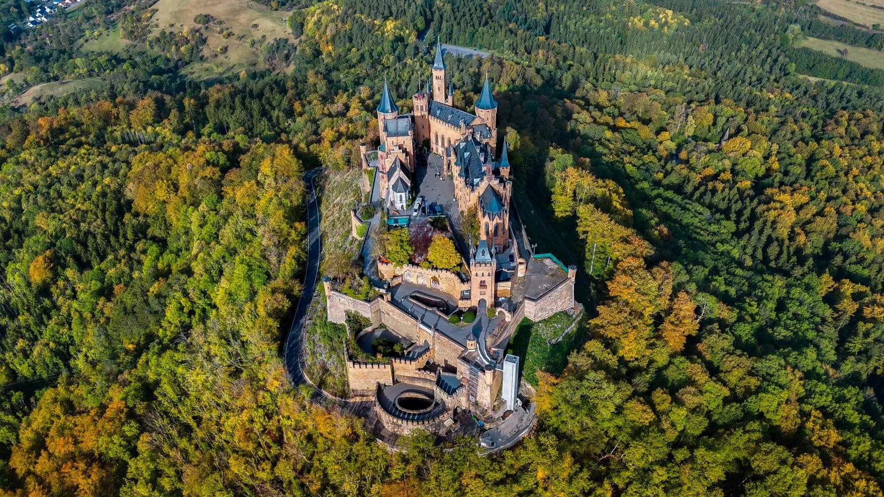 Kasteel Hohenzollern ligt als een kroon boven het bosrijke landschap, met torens en muren die scherp afsteken tegen de herfstkleuren – een iconisch voorbeeld van mooie kastelen in Duitsland.