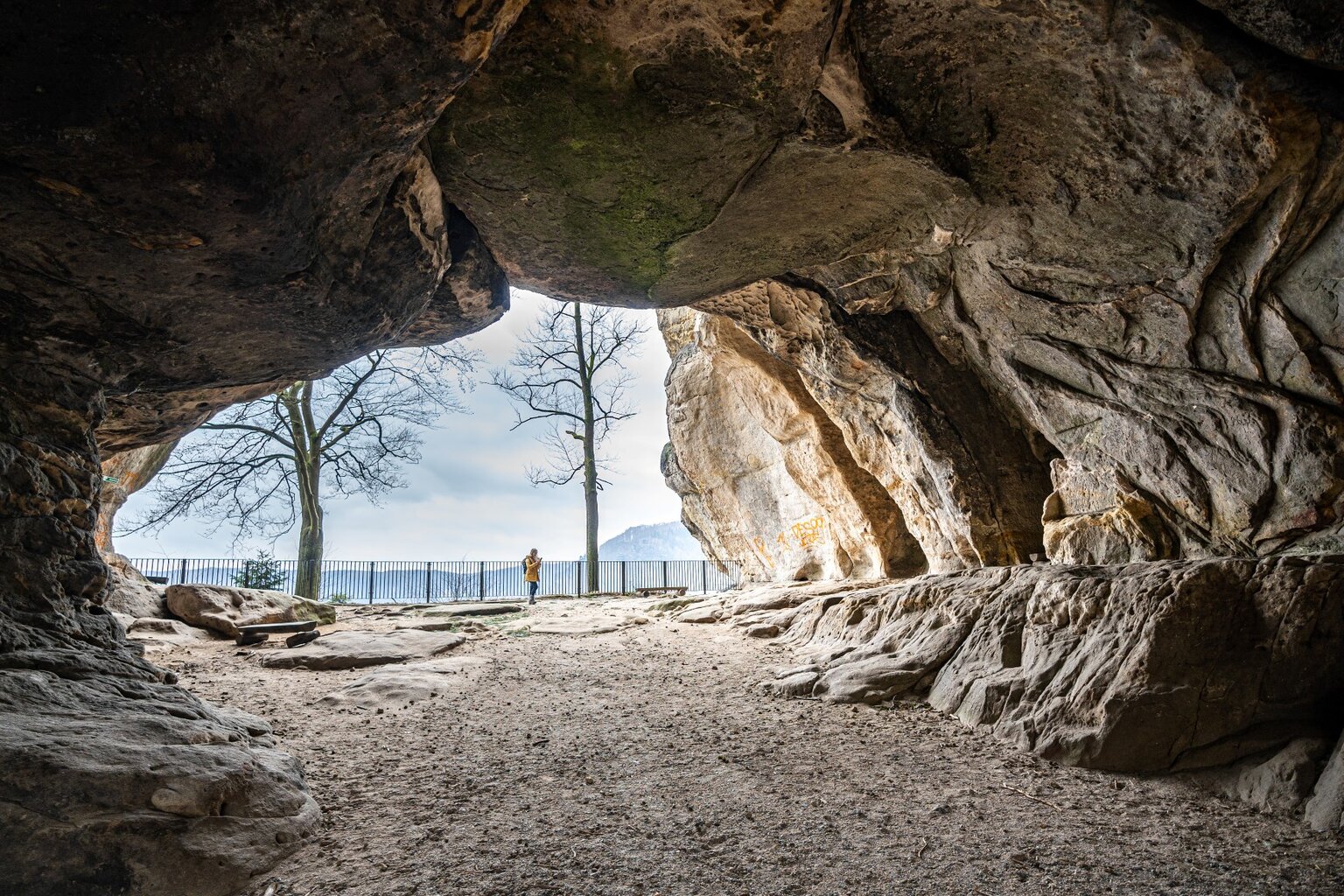 Uitzicht vanuit een rotsschuilplaats op het winterse landschap van de Sächsische Schweiz, waar Wandelen in Saksisch Zwitserland langs ruige zandsteenformaties een avontuurlijk karakter krijgt.