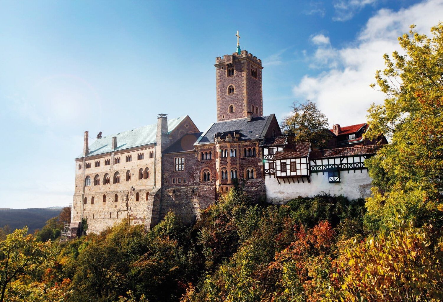 De Wartburg in Thüringen, hoog boven het herfstkleurige landschap, met robuuste torens en vakwerkgebouwen die samen een iconisch beeld vormen van de mooiste kastelen in Duitsland en het leven van ridders en vorsten tot leven brengen.