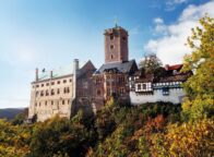 De Wartburg in Thüringen, hoog boven het herfstkleurige landschap, met robuuste torens en vakwerkgebouwen die samen een iconisch beeld vormen van de mooiste kastelen in Duitsland en het leven van ridders en vorsten tot leven brengen.