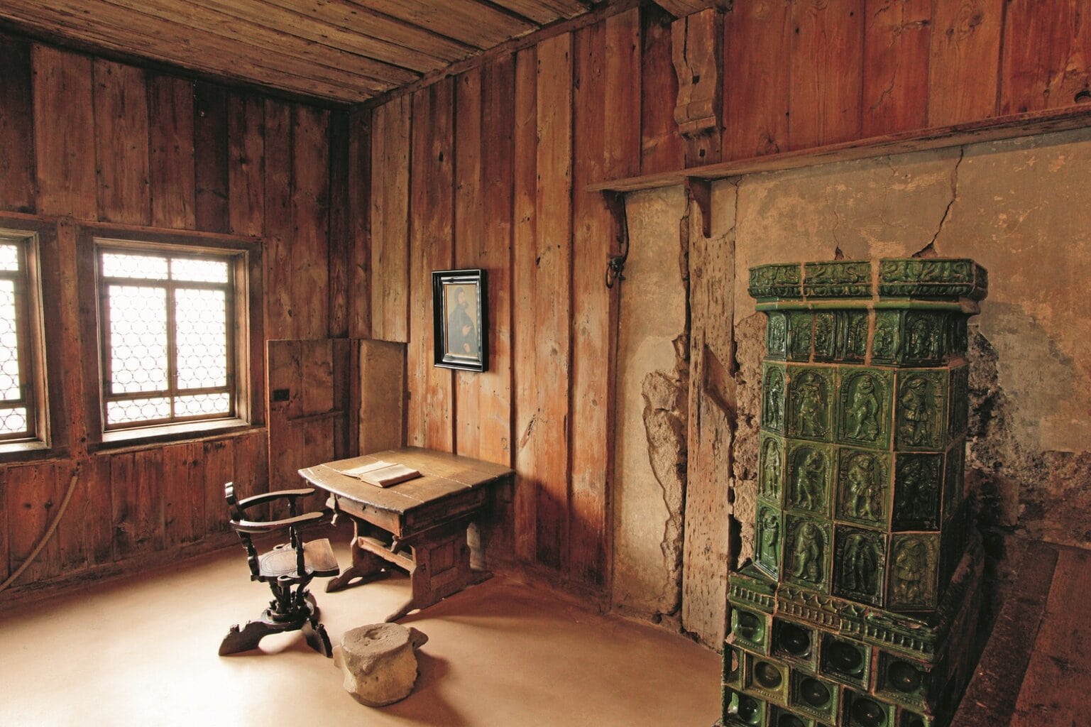 Historische Lutherkamer in de Wartburg met houten wanden, klein schrijfbureau en groene tegelkachel, een sfeervolle ruimte waar je de middeleeuwen voelt en je waant tussen de mooiste kastelen in Duitsland.
