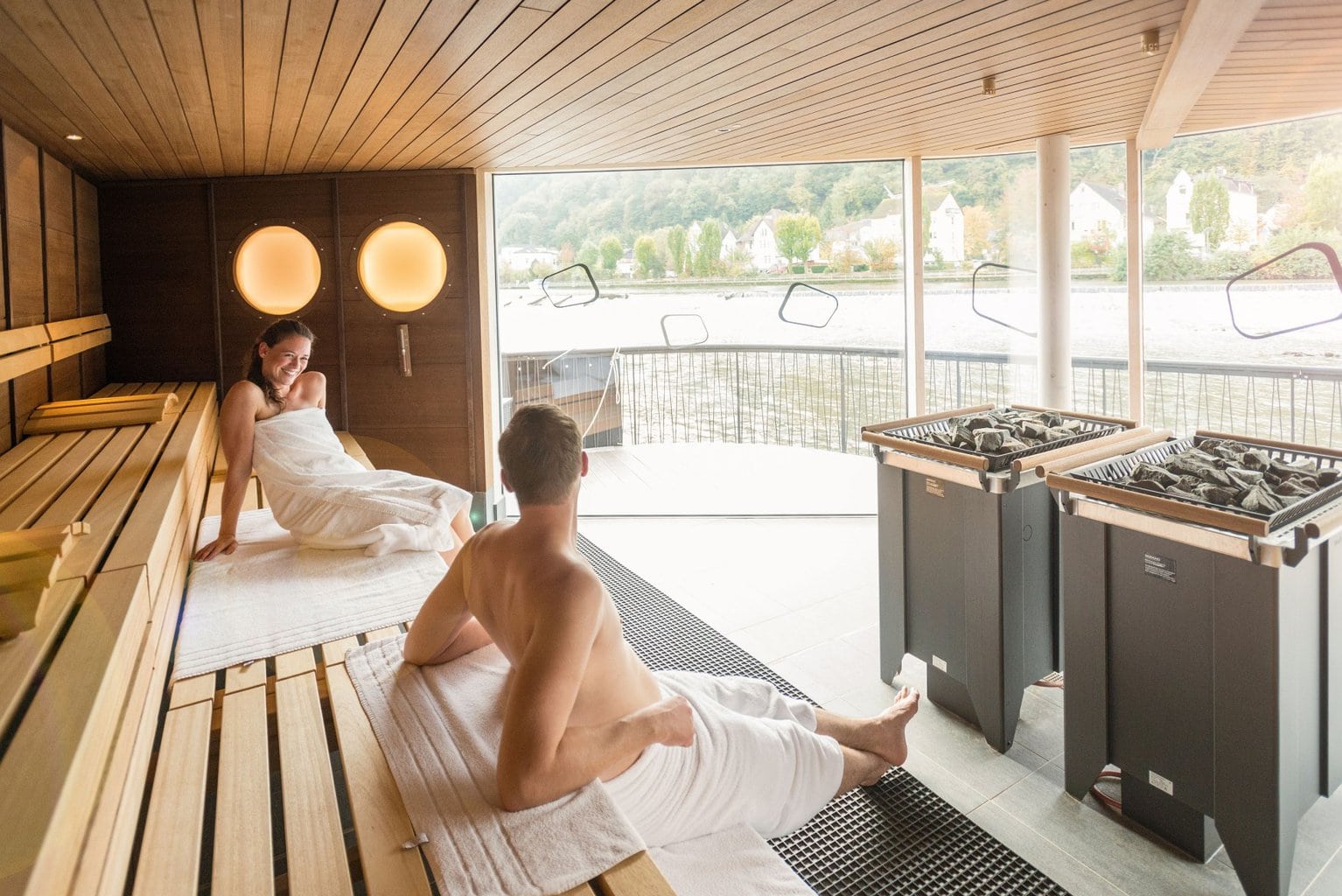 Je midden in de natuur bevinden en toch omringd zijn door de behaaglijke warmte van het thermale bad, dat is de ervaring die de drijvende riviersauna van de Emser Therme je biedt. De panoramasauna op de Lahn is de eerste riviersauna van Duitsland en biedt een uniek uitzicht op het Lahndal en de hoge Malberg. Het zonnedek nodigt uit om daarna te ontspannen of af te koelen. “Wellness aan de rivier” is het motto van de Emser Therme. De afgeronde vormen van de rivierkiezelstenen, warme kleuren en natuurlijke materialen komen terug in de architectuur. Het kostbare thermale water van Ems, het symbool van het kuuroord Bad Ems, bestaat uit meer dan dertig mineralen en sporenelementen.