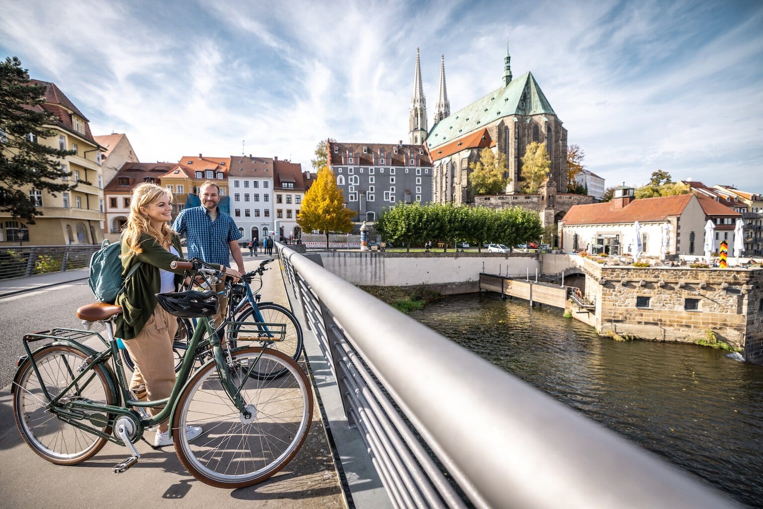 Twee mensen nemen op een brug in Görlitz even pauze tijdens hun fietstocht over het Oder-Neiße-fietspad