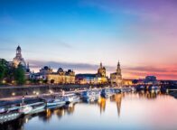 De Elbe ligt op de voorgrond. Daarop varen enkele schepen die aan de oever van de stad Dresden liggen. De lucht is bij de avondzon in rode en paarse tinten die overgaan in het blauw van de hemel. In de Elbe worden het avondlicht en het silhouet van de stad weerspiegeld.