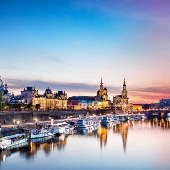 De Elbe ligt op de voorgrond. Daarop varen enkele schepen die aan de oever van de stad Dresden liggen. De lucht is bij de avondzon in rode en paarse tinten die overgaan in het blauw van de hemel. In de Elbe worden het avondlicht en het silhouet van de stad weerspiegeld.