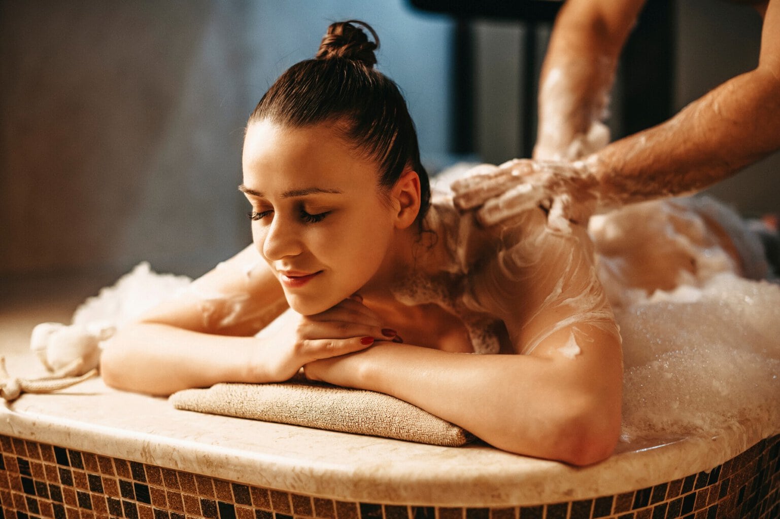 Een vrouw ontspant zich tijdens een zeepschuimmassage in een hamam