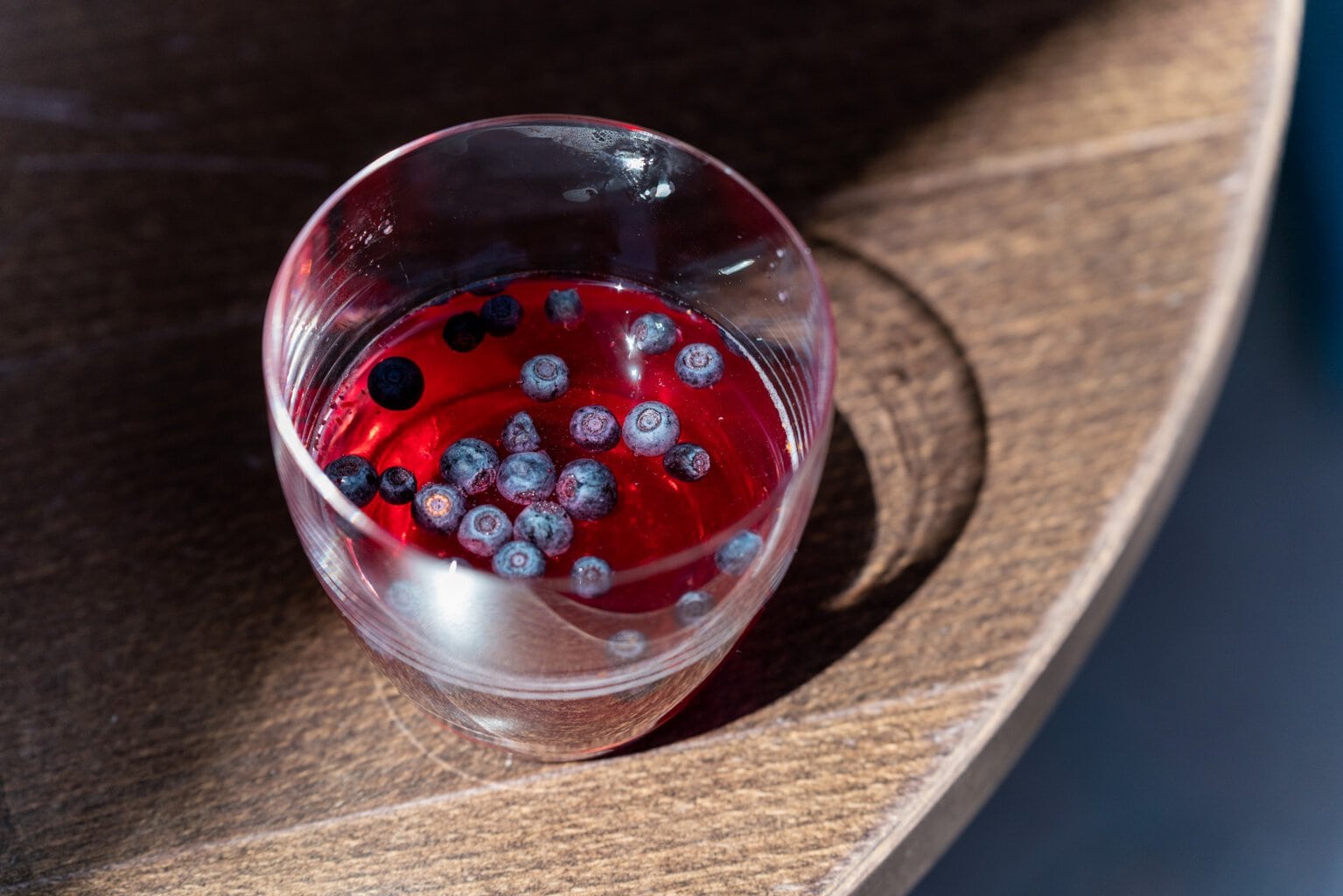 Op een houten tafel staat een cocktail met bosbessen