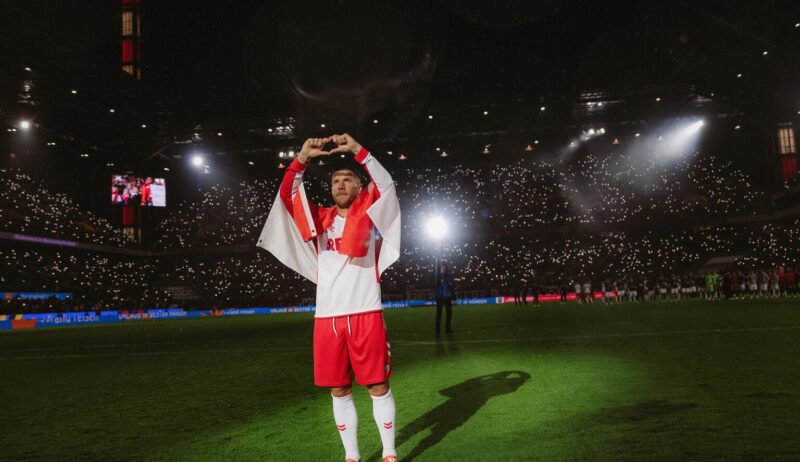 Foto uit de Netflix-documentaire ‘Poldi’: voetballer Lukas Podolski staat in het stadion op het veld in het wit-rode shirt van 1. FC Köln en vormt met zijn vingers een hartje.