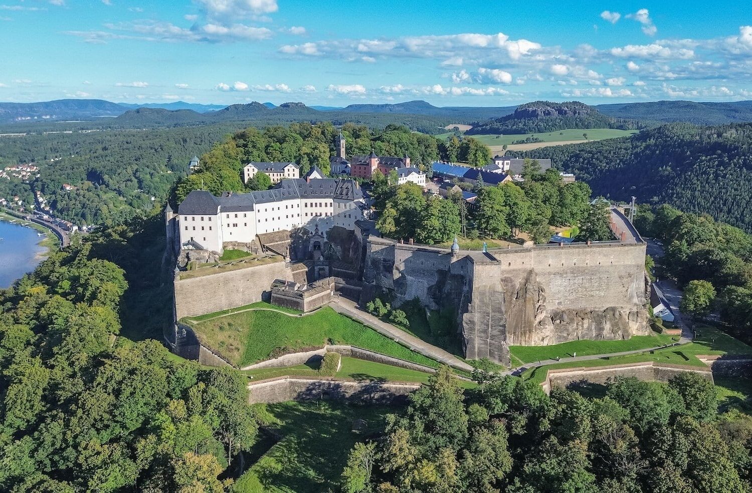 Het fort Königsburg steekt uit tussen de groene bomen. De foto is vanuit vogelperspectief genomen; achter het fort is de stad Königsburg te zien en links stroomt de Elbe.