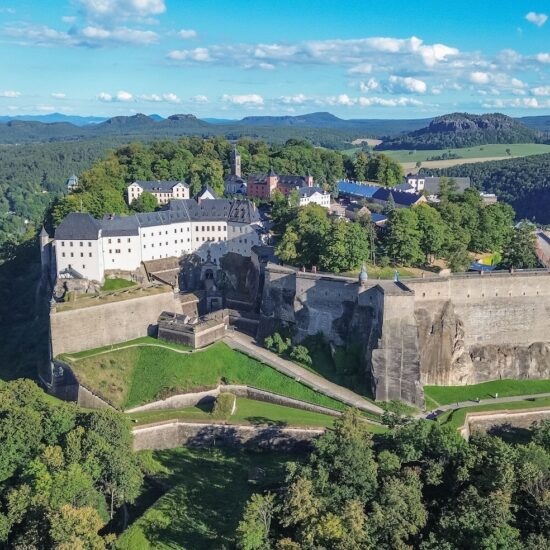 Het fort Königsburg steekt uit tussen de groene bomen. De foto is vanuit vogelperspectief genomen; achter het fort is de stad Königsburg te zien en links stroomt de Elbe.