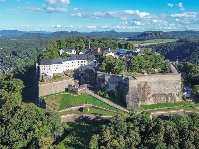 Het fort Königsburg steekt uit tussen de groene bomen. De foto is vanuit vogelperspectief genomen; achter het fort is de stad Königsburg te zien en links stroomt de Elbe.