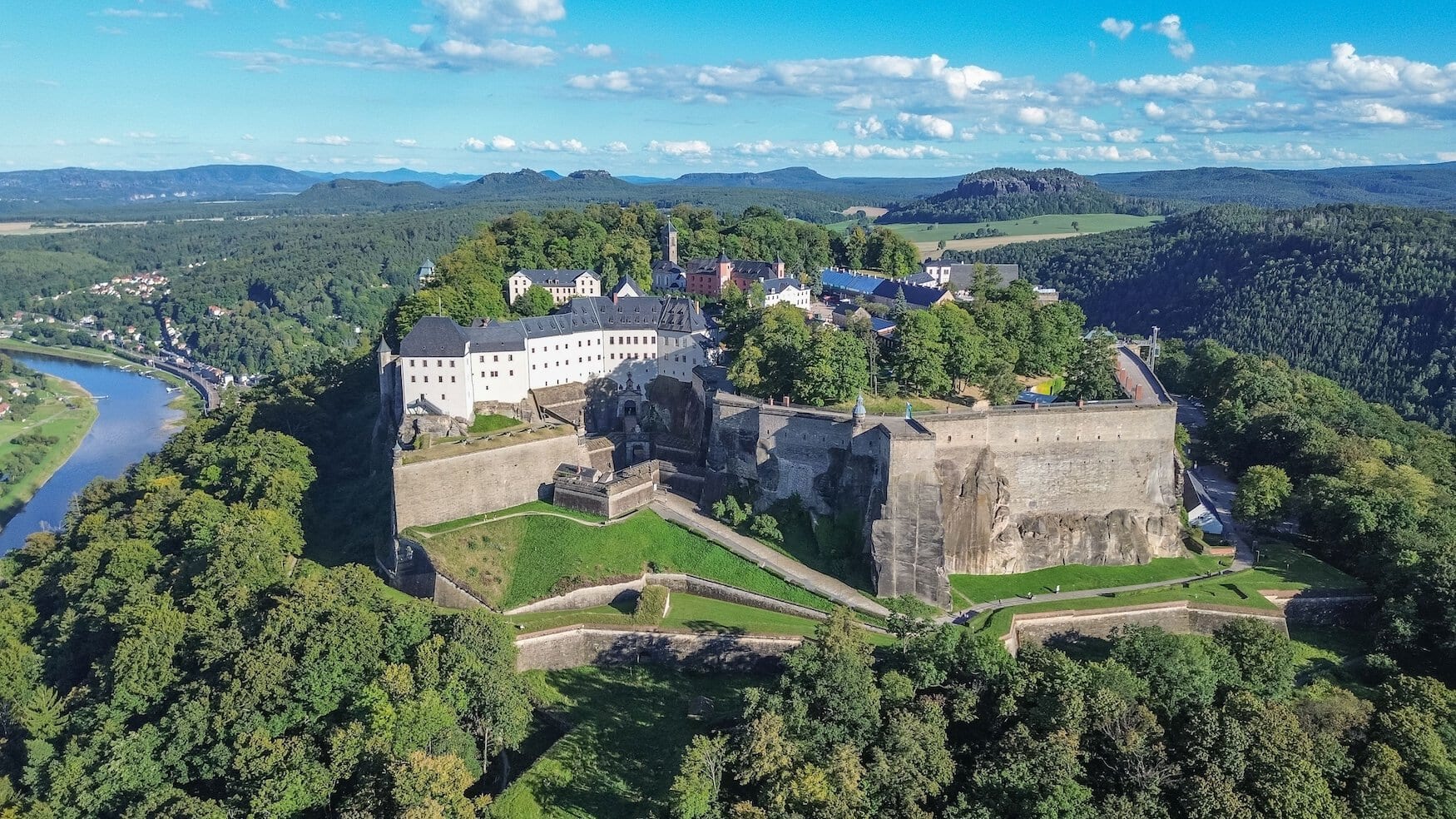 Het fort Königsburg steekt uit tussen de groene bomen. De foto is vanuit vogelperspectief genomen; achter het fort is de stad Königsburg te zien en links stroomt de Elbe.