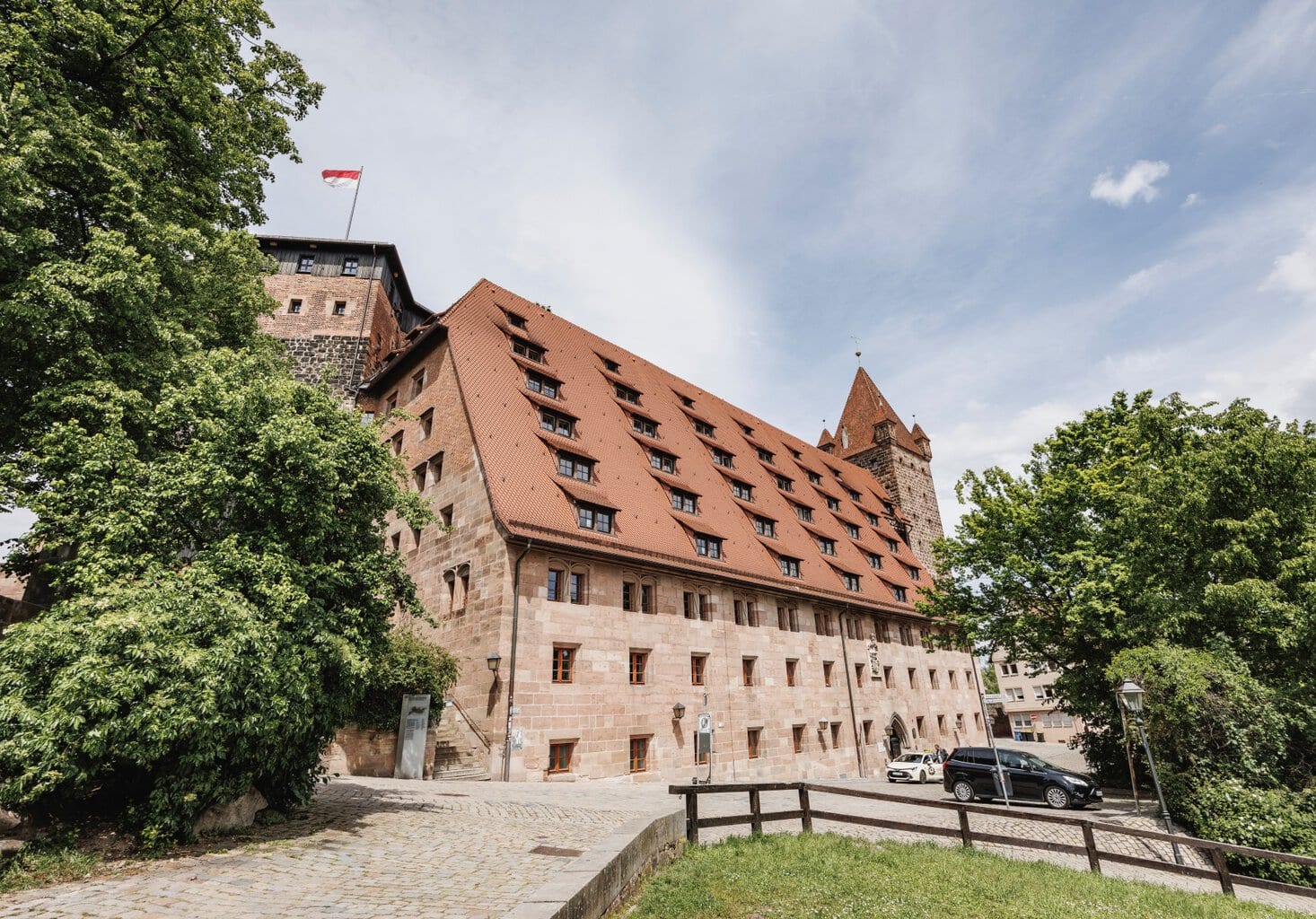 Een van de gebouwen in de Kaiserburg in Neurenberg in markante rode zandsteen, met veel ramen in de muur en in het dak.